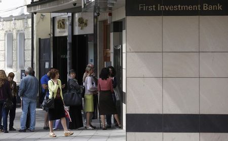 © Reuters. People queue outside a branch of Bulgaria's First Investment Bank, in Sofia