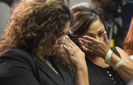 © Reuters. Family members of GM crash victims wipe their eyes as Kenneth Feinberg, a victims compensation lawyer hired by GM, speaks in Washington