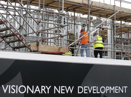 © Reuters. Construction workers stand on scaffolding at a housing development project in south London