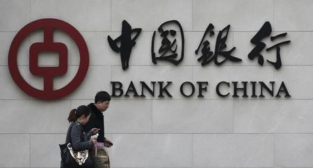 © Reuters. Pedestrians walk past a Bank of China sign at its branch in Beijing