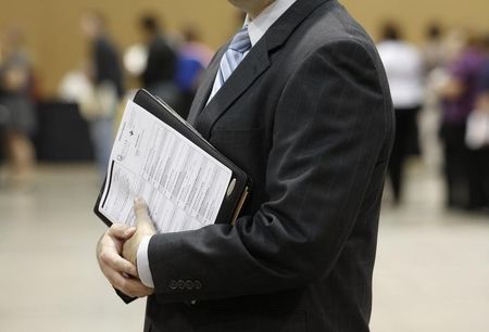 © Reuters. A job seekers holds his binder filled with resumes at the Phoenix Convention Center in Phoenix, Arizona