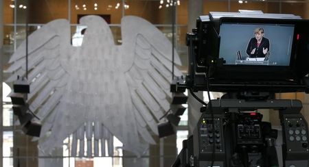 © Reuters. German Chancellor Merkel is pictured on TV camera monitor as she addresses the Bundestag