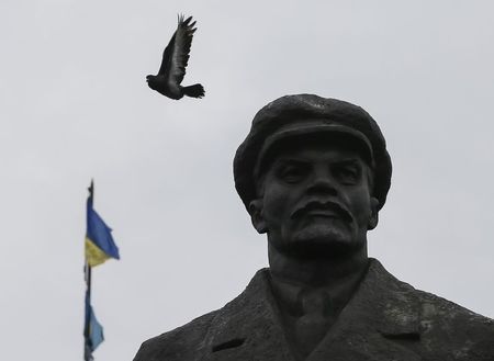 © Reuters. A pigeon flies from a monument of Soviet leader Vladimir Lenin in front of the mayor's office, with Ukrainian flags in central Slaviansk