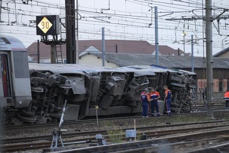 © Reuters. Rescue workers stand next to the wreckage of a derailed intercity train at the Bretigny-sur-Orge station near Paris