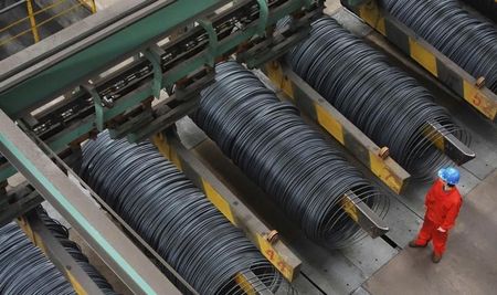 © Reuters. Employee stands next to coils of steel inside a factory in Dalian