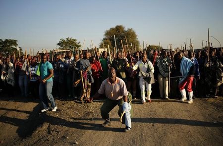 © Reuters. Miners on strike chant slogans as they march in Nkaneng township outside the Lonmin mine in Rustenburg