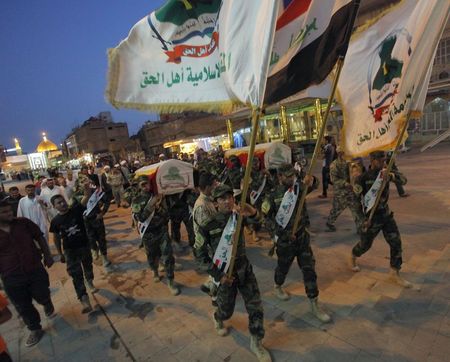 © Reuters. Members of Shi'ite group Asaib Ahl al-Haq carry coffins of fighters from their group who were killed during clashes with militants of the Islamic State, during a funeral in Najaf