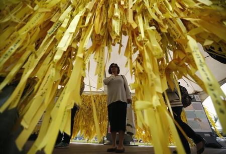 © Reuters. A woman reads messages on yellow ribbons dedicated to dead and missing passengers of the sunken ferry Sewol, at Seoul City Hall Plaza in Seoul