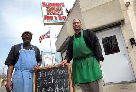 © Reuters. Kevin Ward (L) and Charlie Monagan, co-owners of Slabbee's Ribs & Soul, stand in front of their recently opened take-out rib joint in Detroit, Michigan April 17, 2013. 