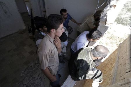 © Reuters. Free Syrian Army fighters look through a window overlooking al-Tarraf checkpoint after seizing it from forces of Syria's President Assad in southern Idlib countryside