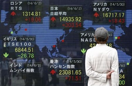 © Reuters. A pedestrian looks at an electronic board  outside a brokerage in Tokyo