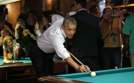 © Reuters. U.S. President Obama shoots pool during stop in a bar in Denver