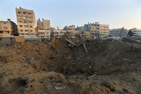 © Reuters. Palestinians stand atop the rubble of a house which police said was destroyed in an Israeli air strike in Gaza City