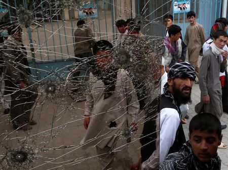 © Reuters. People look at a cracked side window of a bus which was damaged at bomb blasts in Kabul