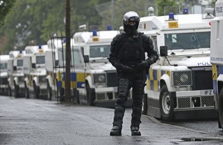 © Reuters. A police officer dressed in riot gear stands near a barrier erected by the police to prevent an Orange Order parade passing the mainly Nationalist Ardoyne area of North Belfast