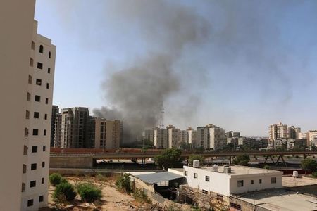 © Reuters. Smoke rises near buildings after heavy fighting between rival militias broke out near the airport in Tripoli