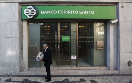 © Reuters. A man reads a newspaper as he passes near an office of Portuguese bank Banco Espirito Santo in Lisbon