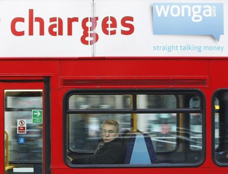 © Reuters. A passenger sits on a bus beneath an advert for short term loan company Wonga in London