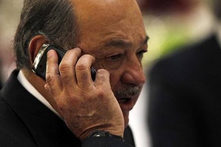 © Reuters. Mexican billionaire Carlos Slim speaks on his mobile phone during an official visit by Portugal's Prime Minister Pedro Passos Coelho at the National Palace in Mexico City