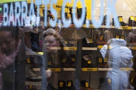 © Reuters. Passers-by are reflected in the display window of Barratts shoe shop in central London