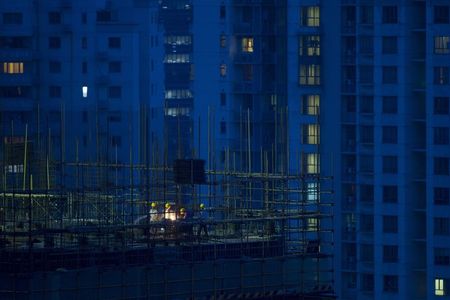 © Reuters. Labourers work atop scaffolding at a residential construction site in Shanghai