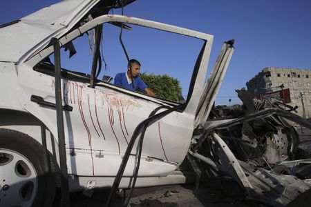 © Reuters. Rafah, un ragazzo palestinese accanto ai resti di un'auto colpita nel coros di un attacco aereo israeliano