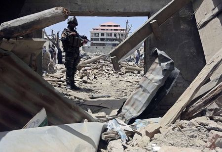 © Reuters. An Afghan security personnel stands guard at the site of yesterday's car bomb attack on a market in Urgon district, Paktika