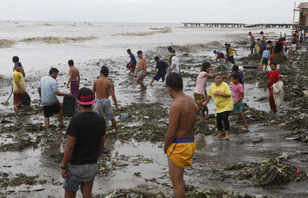 © Reuters. Moradores à beira-mar após a passagem do tufão Rammasun, no litoral da cidade de Rosário, ao sul de Manila