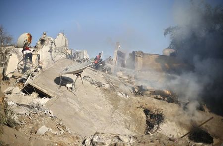 © Reuters. A Palestinian firefighter extinguishes a fire amongst the remains of a house which police said was destroyed in an Israeli air strike in Gaza City