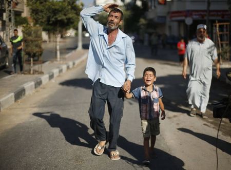 © Reuters. Pai e irmão de um menino que foi morto numa praia de Gaza após ataque de Israel, de acordo com médicos