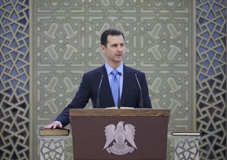 © Reuters. Syria's President Bashar al-Assad places his right hand on a Koran as he is sworn in for a new seven-year term, at al-Shaab presidential palace in Damascus