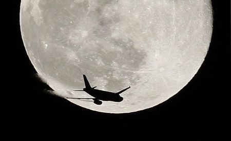 © Reuters. An airplane is silhouetted against a full moon in the sky over London