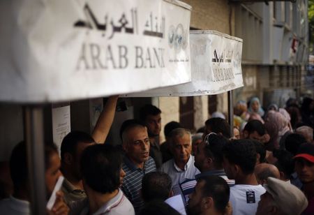 © Reuters. Palestinians wait to withdraw cash from an ATM machine outside a bank in Gaza City