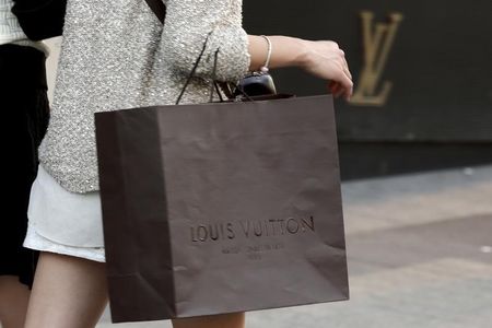 © Reuters. A woman walks with a Louis Vuitton shopping bag as she leaves a Louis Vuitton store in Paris