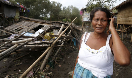 © Reuters. Mulher lamenta ao lado de sua casa destruída pelo tufão Rammasun, na cidade costeira de Batangas, ao sul de Manila, nas Filipinas  