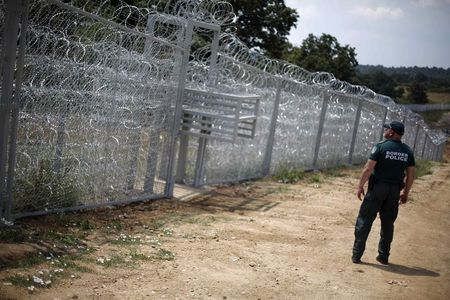 © Reuters. A Bulgarian border policeman stands in front of a barbed wire fence on the Bulgarian-Turkish border