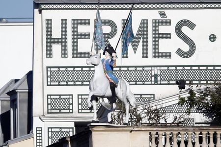 © Reuters. A view shows a horse rider waving two Hermes scarves in front of the logo of French luxury group Hermes on the group's headquarters building roof in Paris