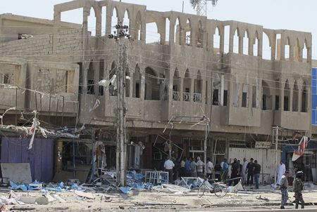 © Reuters. Residents     gather at the scene of one of a series of car bomb attacks that struck Baghdad