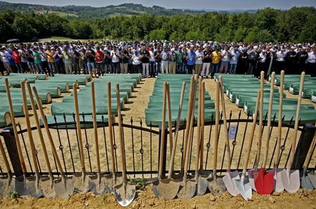 © Reuters. Bosnian Muslims pray in front of coffins of their relatives during a mass funeral in the village of Biscani