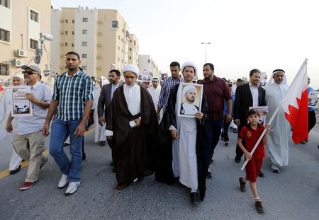 © Reuters. General Secretary of Bahrain's main opposition party Al Wefaq, Sheikh Ali Salman holding banner with photo of Shi'ite scholar, Sheikh Hasan Najaty, marches during an anti-government protest in Manama