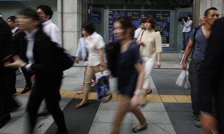 © Reuters. Pedestrians walk past at an electronic board outside a brokerage in Tokyo