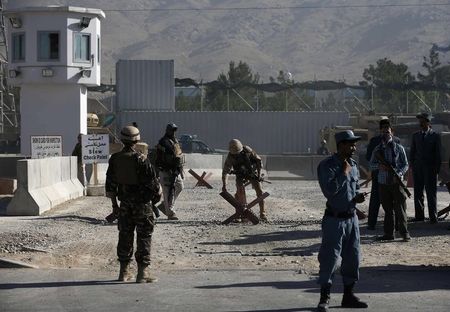 © Reuters. Afghan and foreign security personnel stand guard at the site of a blast, outside the counter-narcotics office near the Kabul International Airport