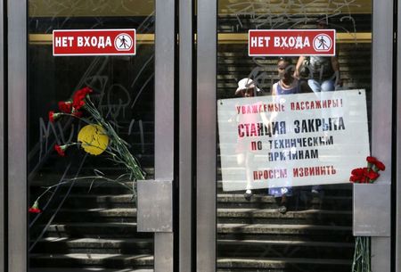 © Reuters. Flowers in memory of victims of Tuesday's accident are left next to a sign informing passengers that the station is closed due to technical reasons, at the entrance to a metro station in Moscow