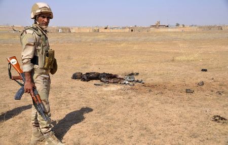 © Reuters. An Iraqi soldier stands near the body of a member of the Islamic State, who died during clashes with Iraqi forces, in Tikrit