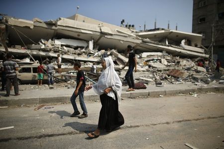 © Reuters. Palestinos caminham próximos aos escombros de um prédio residencial que a polícia diz ter sido destruído em um ataque aéreo de Israel, em Gaza