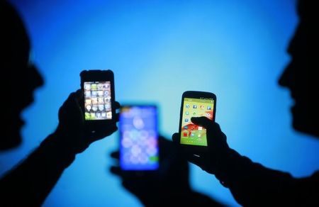 © Reuters. Men pose with Samsung Galaxy S3 Nokia Lumia 820 and iPhone 4 smartphones in photo illustration in Zenica