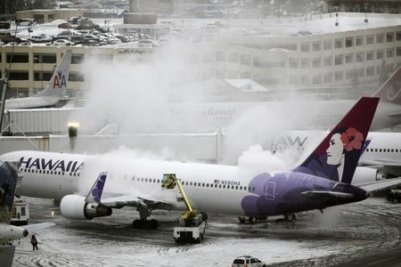 © Reuters. A Hawaiian Airlines plane, delayed for approximately 4 hours, undergoes de-icing before takeoff at Seattle-Tacoma International Airport