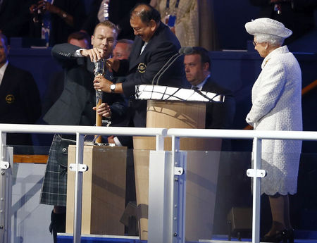 © Reuters. Britain's Queen Elizabeth watches as Prince Imran of Malaysia and Chris Hoy struggle to open the baton containing her message during the opening of the 2014 Commonwealth Games at Celtic Park in Glasgow, Scotland,