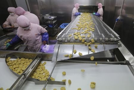 © Reuters. Employees work at a production line prior to a seizure at the Husi Food factory in Shanghai