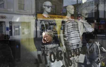 © Reuters. A pedestrian talks on the phone as she walks along King Street, the main shopping street in Kilmarnock